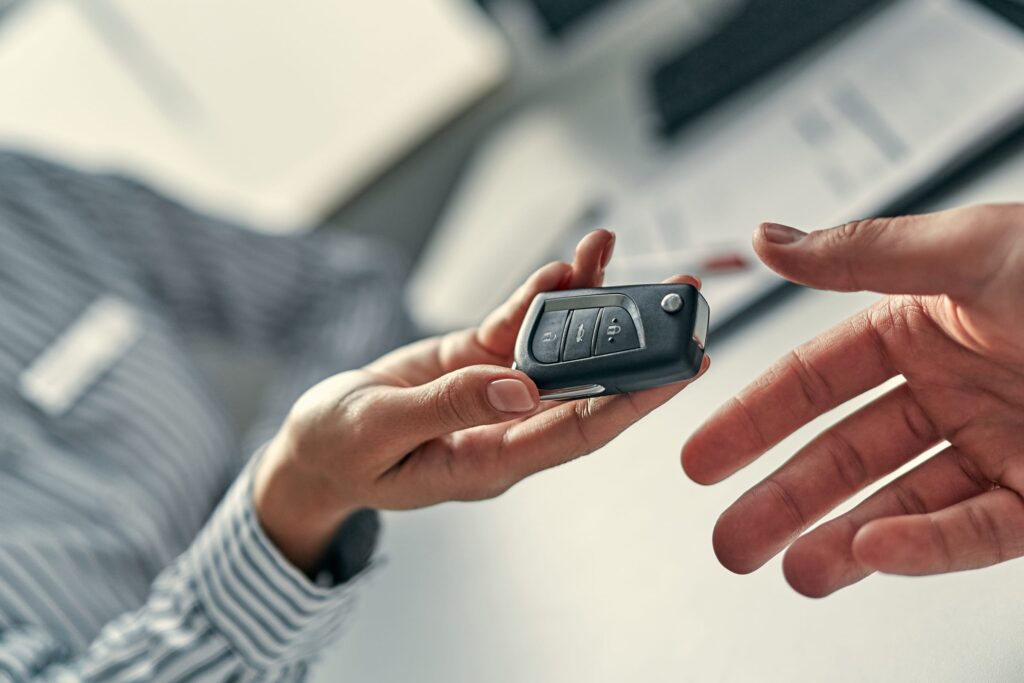 Hands exchanging a vehicle key with Evo Auto Locksmith call-to-action banner